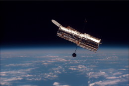 Photograph of a space telescope above the earth.