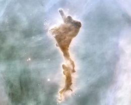 Photograph of a dark cloud in the midst of a wispy nebula.