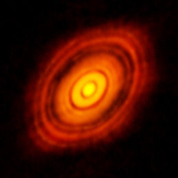 Image reveals a tilted oval structure of an orange disk containing a number of concentric gaps and rings.