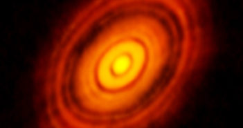 Image reveals a tilted oval structure of an orange disk containing a number of concentric gaps and rings.