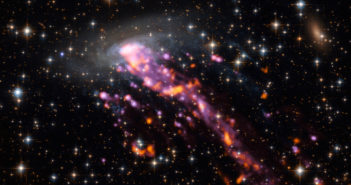 Image of a galaxy with a long, streaming tail stretched out behind it.