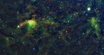 False-color photograph showing wispy molecular clouds in a space field.