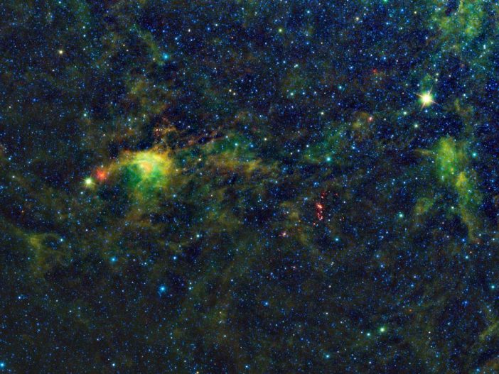 False-color photograph showing wispy molecular clouds in a space field.