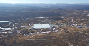 Aerial image of a large rectangular structure surrounded by a circle in the landscape. Circular tanks are visible to the right of the structure.