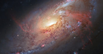 dark dust lanes spiral around the glowing central bulge of M106