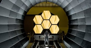 photograph of an engineer standing in front of JWST mirror segments