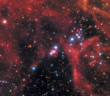An image of the night sky featuring a wispy gas cloud and many stars. Tiny and at the center, the supernova remnant is flanked by a pair of rings of debris.