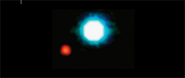 An image of a large, bright white star, center, and a much fainter, smaller, red star at lower left.