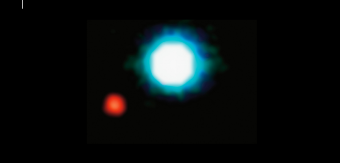 An image of a large, bright white star, center, and a much fainter, smaller, red star at lower left.