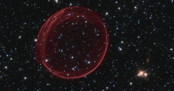A circular red gas bubble, more opaque on the edges than in the center, sits in a field of stars.