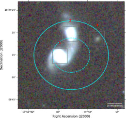 A photograph of two nearby spiral galaxies, with cyan ellipses overplotted to show the uncertainty in the location of the FRB.