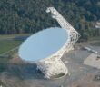 A photograph of a large radio dish taken during the day from above.