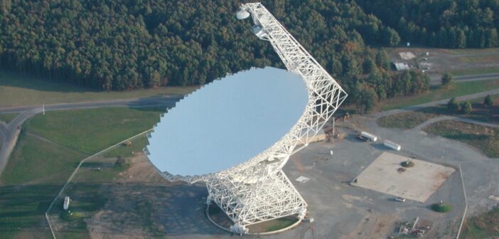 A photograph of a large radio dish taken during the day from above.