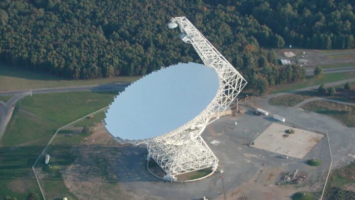 A photograph of a large radio dish taken during the day from above.