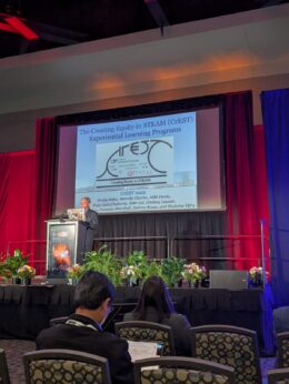 Prof. Raja GuhaThakurta beginning his 2025 AAS Education Prize Plenary Lecture at the AAS 247 meeting in Phoenix, Arizona. An overview of various CrEST programs is seen on the screen behind.