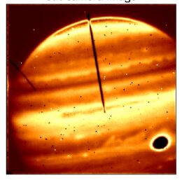 A photograph of Jupiter seen in red/orange false color with a dark stripe down the middle.