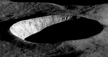 An oblique-angle photograph of a deep crater half in shadow.