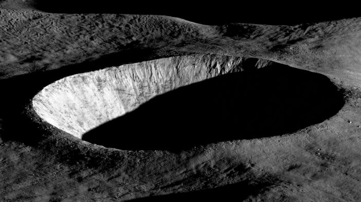 An oblique-angle photograph of a deep crater half in shadow.